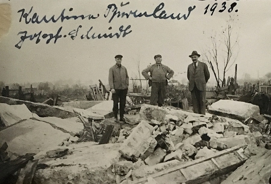 3 Männer stehen vor Trümmern eines Gebäudes